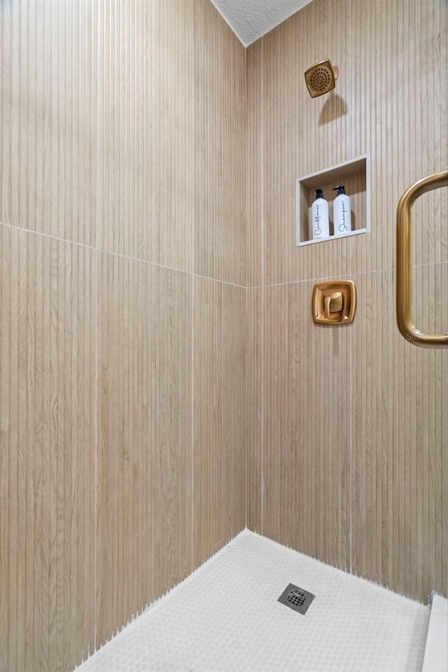 full bathroom featuring tiled shower and a textured ceiling
