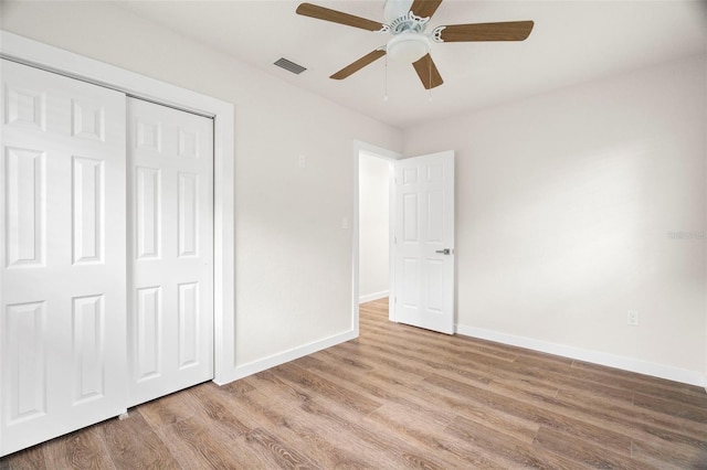 unfurnished bedroom featuring baseboards, wood finished floors, a closet, and ceiling fan