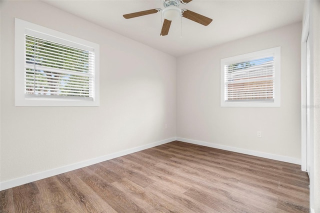 unfurnished room featuring plenty of natural light, wood finished floors, baseboards, and a ceiling fan