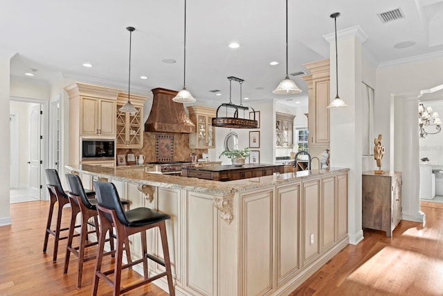 17129 Breeders Cup Dr, Odessa, FL 33556 - kitchen with cream cabinets, premium range hood, decorative backsplash, built in microwave, and light wood finished floors