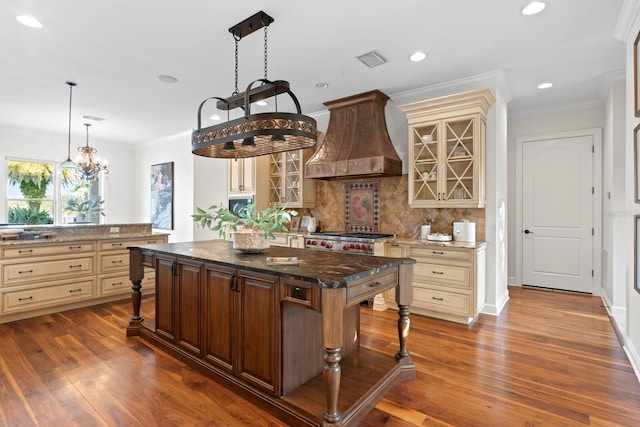 17129 Breeders Cup Dr, Odessa, FL 33556 - kitchen with cream cabinetry, wall chimney range hood, glass insert cabinets, backsplash, and ornamental molding