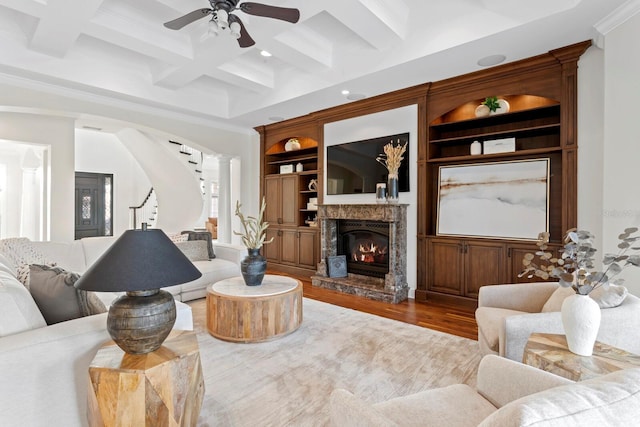 17129 Breeders Cup Dr, Odessa, FL 33556 - living area with a ceiling fan, ornamental molding, a stone fireplace, coffered ceiling, and wood finished floors