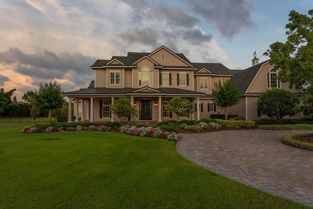 17129 Breeders Cup Dr, Odessa, FL 33556 - view of front of house featuring a standing seam roof, covered porch, curved driveway, and a front yard