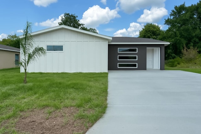 view of property exterior with board and batten siding, a yard, and concrete driveway