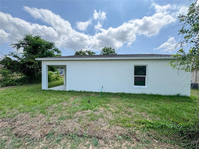 view of side of home with stucco siding and a yard