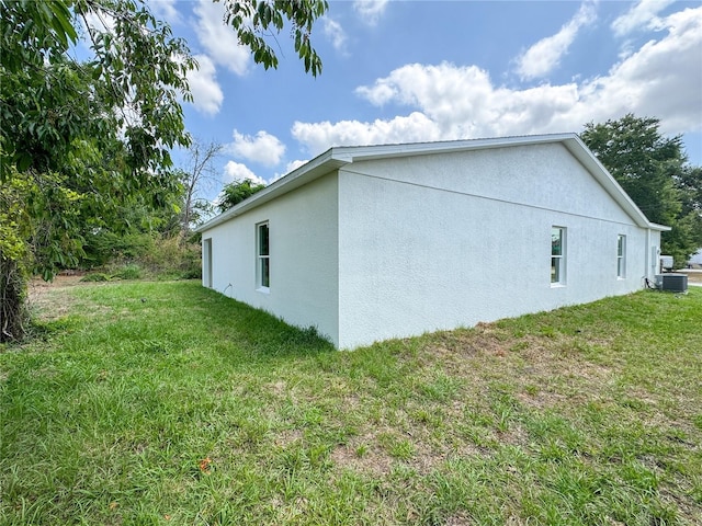 view of home's exterior with stucco siding, central air condition unit, and a yard