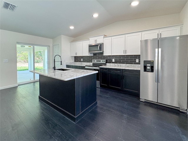 kitchen with appliances with stainless steel finishes, a sink, lofted ceiling, dark wood finished floors, and decorative backsplash