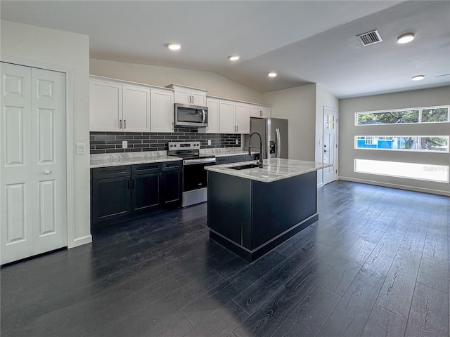 kitchen with stainless steel appliances, a sink, dark wood-style floors, white cabinetry, and lofted ceiling