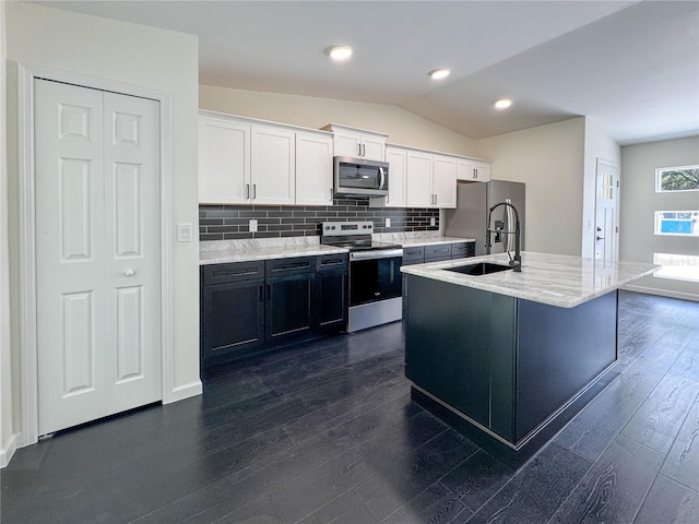 kitchen with appliances with stainless steel finishes, a sink, white cabinetry, backsplash, and dark wood-style floors