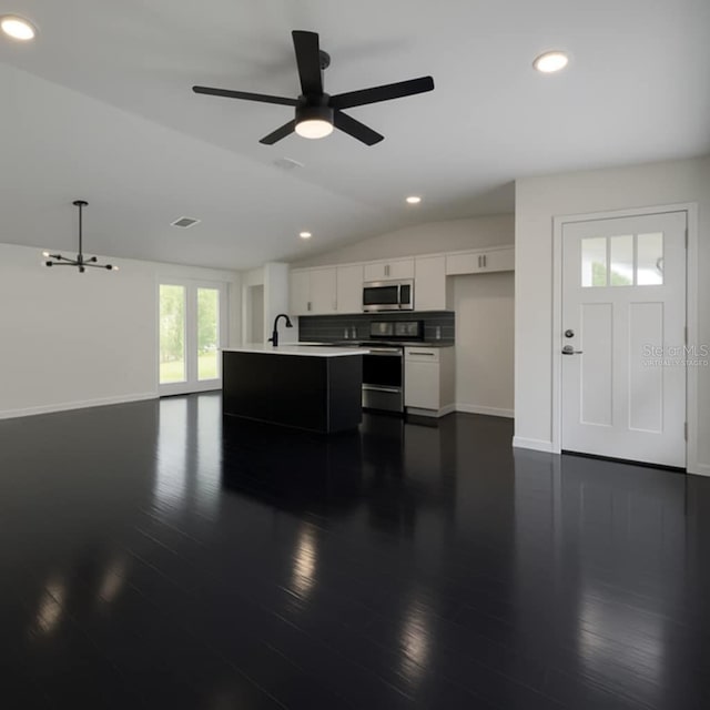 kitchen with stainless steel appliances, vaulted ceiling, open floor plan, baseboards, and light countertops