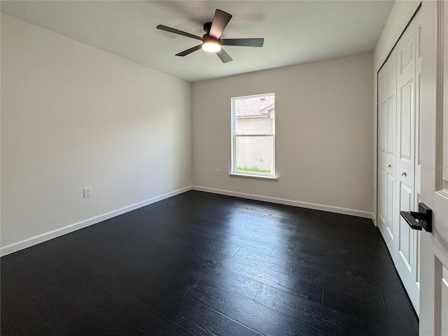 unfurnished bedroom with dark wood finished floors, baseboards, a closet, and a ceiling fan