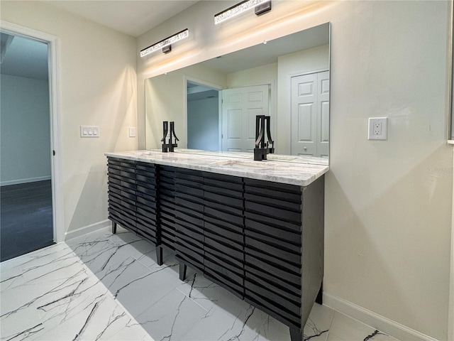 bathroom featuring baseboards, marble look tiles, and double vanity