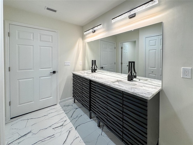 full bath with double vanity, marble finish flooring, and baseboards