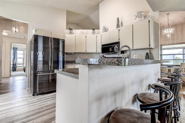 8913 Welsh Way, Hudson, FL 34667 - kitchen featuring black appliances, a textured ceiling, plenty of natural light, light wood-type flooring, and high vaulted ceiling