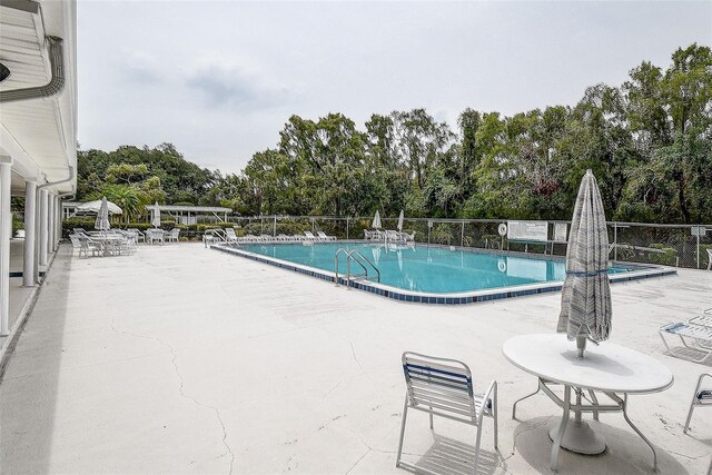 8913 Welsh Way, Hudson, FL 34667 - community pool featuring a patio area, view of scattered trees, and fence