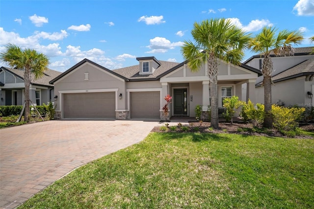 923 Whimbrel Run, Bradenton, FL 34212 - view of front of property featuring stucco siding, decorative driveway, an attached garage, a front lawn, and stone siding