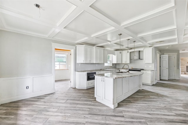 1810 Maryland Ave NE, Saint Petersburg, FL 33703 - kitchen with coffered ceiling, white cabinetry, wall chimney exhaust hood, an island with sink, and light stone countertops