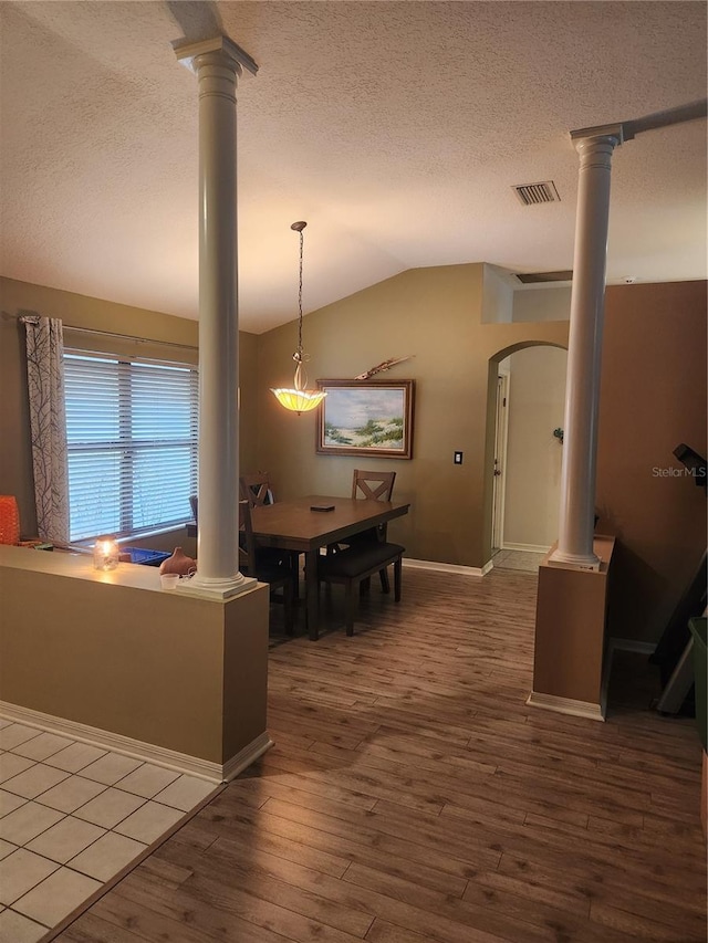 9220 Dayflower Dr, Tampa, FL 33647 - dining room featuring vaulted ceiling, a textured ceiling, ornate columns, wood-type flooring, and arched walkways