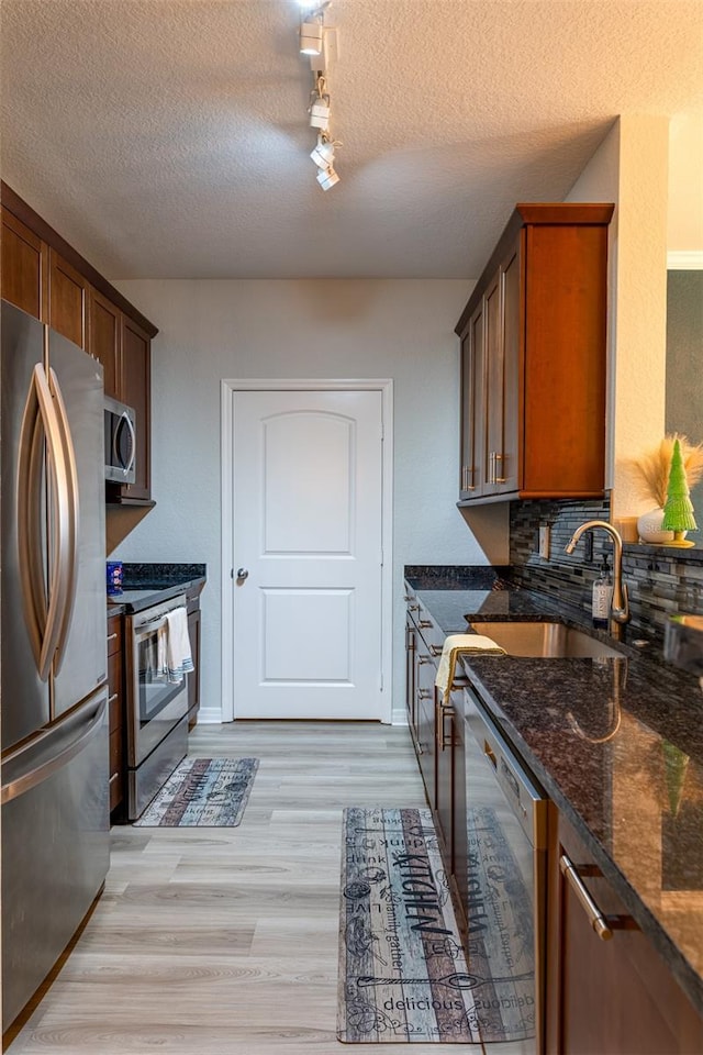 4221 W Spruce St Unit 1303, Tampa, FL 33607 - kitchen with stainless steel appliances, a sink, track lighting, light wood-style floors, and dark stone counters
