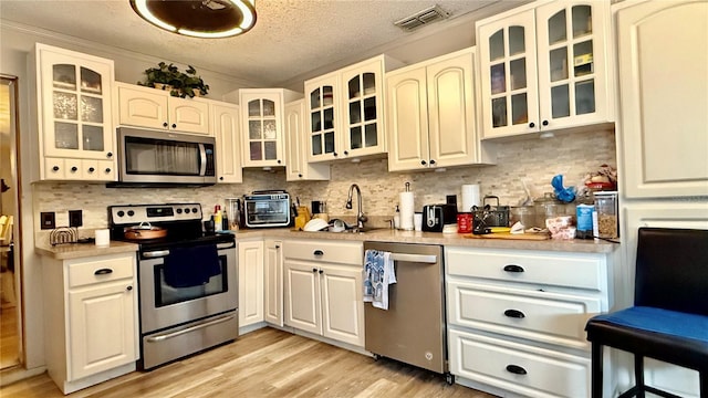 7012 Pin Cherry Ln, Port Richey, FL 34668 - kitchen featuring appliances with stainless steel finishes, a sink, light countertops, backsplash, and a textured ceiling