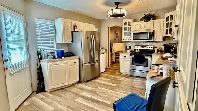 7012 Pin Cherry Ln, Port Richey, FL 34668 - kitchen featuring appliances with stainless steel finishes, decorative backsplash, glass insert cabinets, light wood finished floors, and light countertops