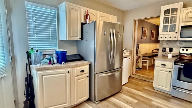 7012 Pin Cherry Ln, Port Richey, FL 34668 - kitchen featuring appliances with stainless steel finishes, light wood finished floors, light countertops, and white cabinetry
