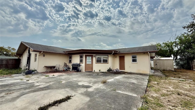 7012 Pin Cherry Ln, Port Richey, FL 34668 - rear view of property with stucco siding, fence, a patio, and driveway