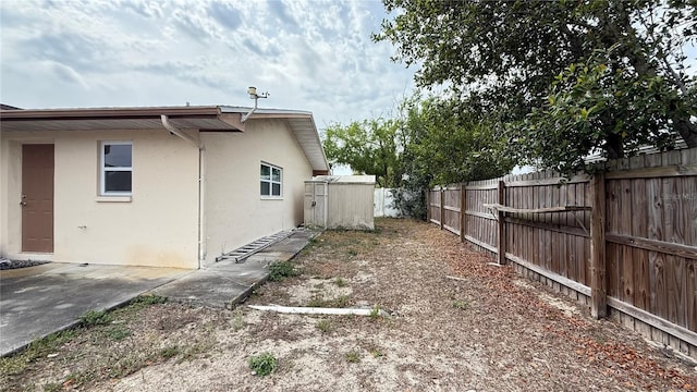 7012 Pin Cherry Ln, Port Richey, FL 34668 - view of home's exterior featuring a fenced backyard, stucco siding, a shed, an outdoor structure, and a patio area