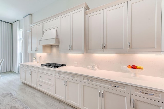 16707 Verona Pl, Bradenton, FL 34202 - kitchen featuring premium range hood, stainless steel gas cooktop, light countertops, and white cabinets