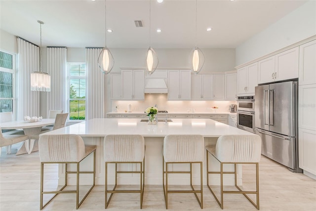16707 Verona Pl, Bradenton, FL 34202 - kitchen featuring stainless steel appliances, custom exhaust hood, light countertops, a kitchen island with sink, and a kitchen breakfast bar