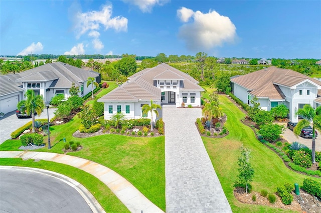 16707 Verona Pl, Bradenton, FL 34202 - view of front facade with decorative driveway, a tile roof, a front lawn, and a residential view