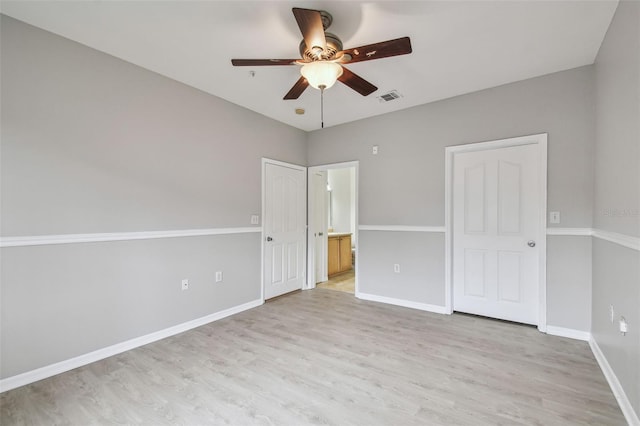 unfurnished bedroom with light wood finished floors, baseboards, ensuite bathroom, and a ceiling fan