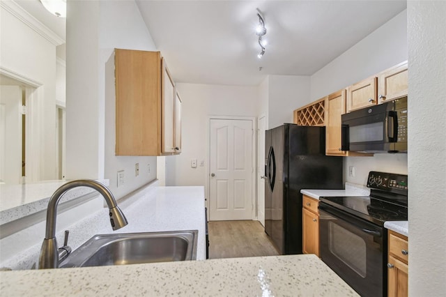 kitchen featuring black appliances, a sink, light wood-style floors, and light stone countertops