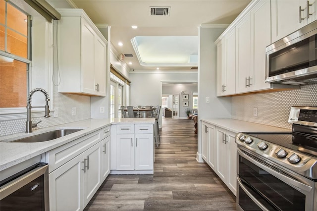 kitchen featuring appliances with stainless steel finishes, a sink, beverage cooler, crown molding, and dark wood finished floors