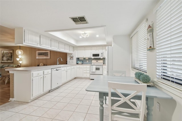 531 Sandy Hook Rd, Treasure Island, FL 33706 - kitchen with white appliances, a raised ceiling, a peninsula, a sink, and light countertops