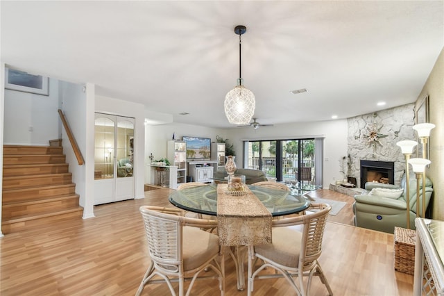 531 Sandy Hook Rd, Treasure Island, FL 33706 - dining area with a stone fireplace, light wood-style flooring, stairs, and a ceiling fan