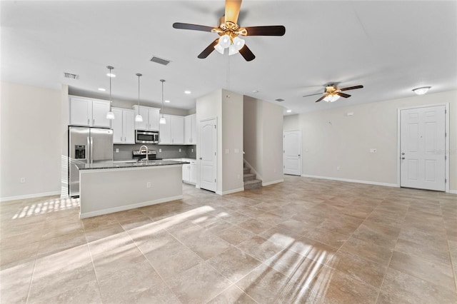13233 Canopy Creek Dr, Tampa, FL 33625 - kitchen with stainless steel appliances, a ceiling fan, open floor plan, white cabinets, and an island with sink