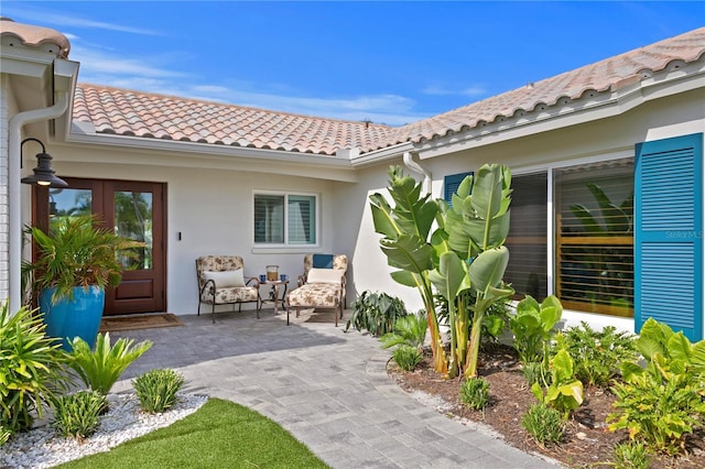 243 Hermosita Dr, St Pete Beach, FL 33706 - view of exterior entry featuring a tile roof, stucco siding, and a patio area