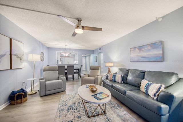 15000 Gulf Blvd Unit 602, Madeira Beach, FL 33708 - living area featuring ceiling fan, light wood-style flooring, baseboards, a textured ceiling, and a chandelier