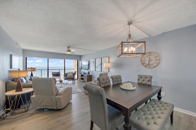 15000 Gulf Blvd Unit 602, Madeira Beach, FL 33708 - dining area featuring a textured ceiling, light wood-style flooring, a chandelier, baseboards, and a ceiling fan