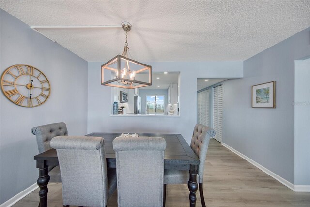 15000 Gulf Blvd Unit 602, Madeira Beach, FL 33708 - dining space featuring a textured ceiling, wood finished floors, a chandelier, and baseboards