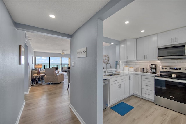 15000 Gulf Blvd Unit 602, Madeira Beach, FL 33708 - kitchen featuring stainless steel appliances, a sink, light wood-style floors, white cabinets, and a textured ceiling