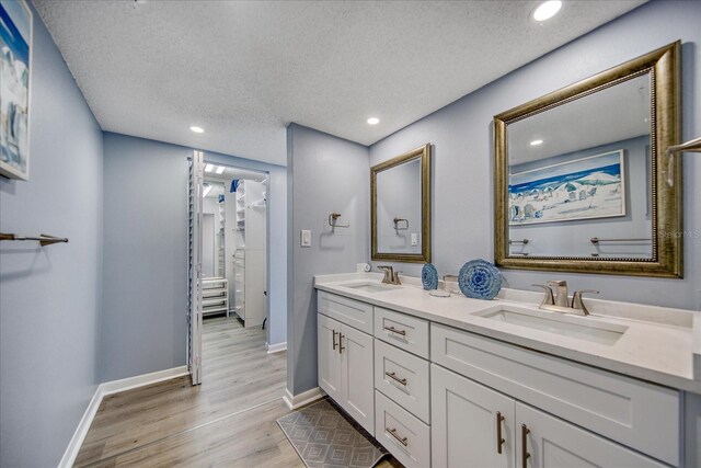 15000 Gulf Blvd Unit 602, Madeira Beach, FL 33708 - full bathroom featuring a textured ceiling, wood finished floors, baseboards, double vanity, and recessed lighting