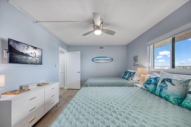 15000 Gulf Blvd Unit 602, Madeira Beach, FL 33708 - bedroom with a textured ceiling, light wood-style flooring, and a ceiling fan
