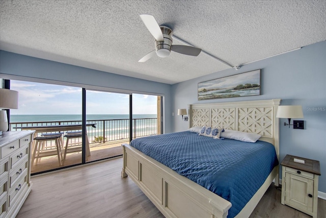 15000 Gulf Blvd Unit 602, Madeira Beach, FL 33708 - bedroom featuring access to outside, light wood-style flooring, a textured ceiling, a water view, and a ceiling fan