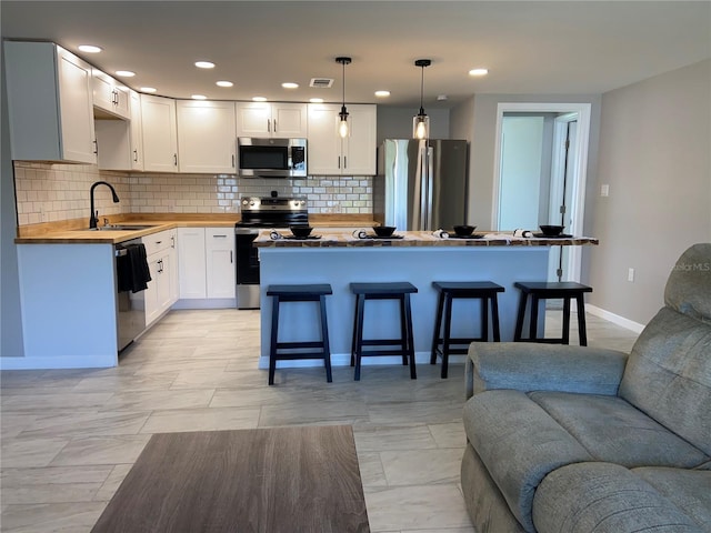 12907 College Hill Dr, Hudson, FL 34667 - kitchen with stainless steel appliances, a sink, open floor plan, backsplash, and butcher block countertops