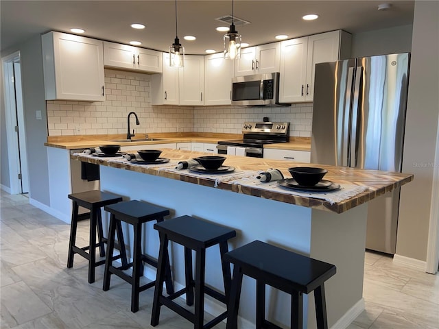12907 College Hill Dr, Hudson, FL 34667 - kitchen featuring butcher block countertops, appliances with stainless steel finishes, light marble finish floors, a sink, and baseboards