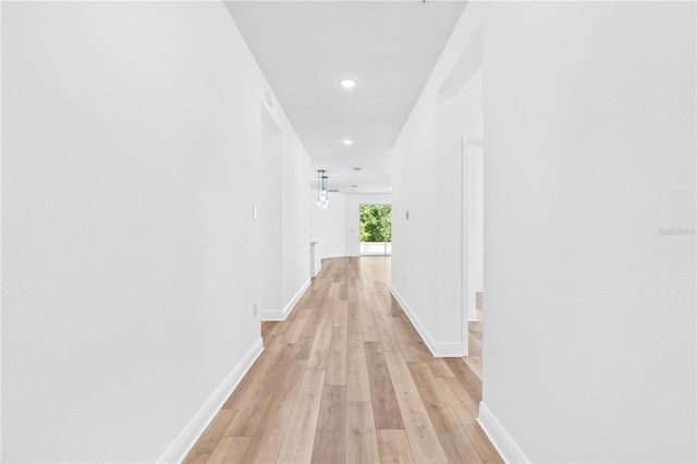 corridor with light wood-type flooring, recessed lighting, and baseboards