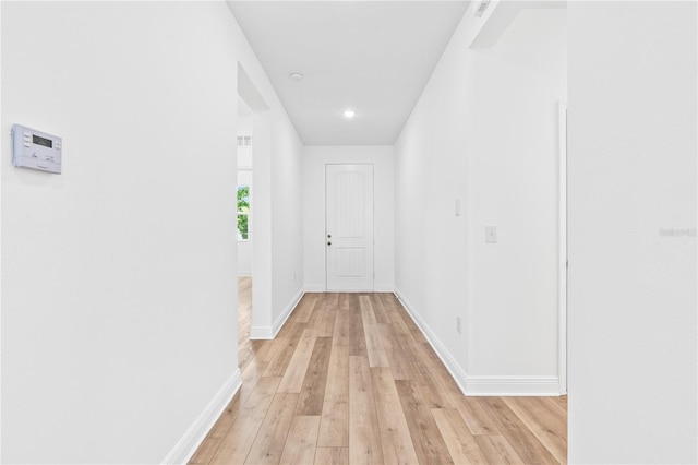 hall featuring light wood-type flooring, baseboards, and recessed lighting