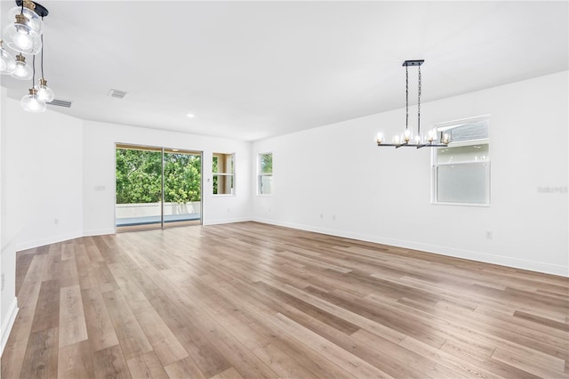 unfurnished room featuring a chandelier, light wood-style floors, and baseboards